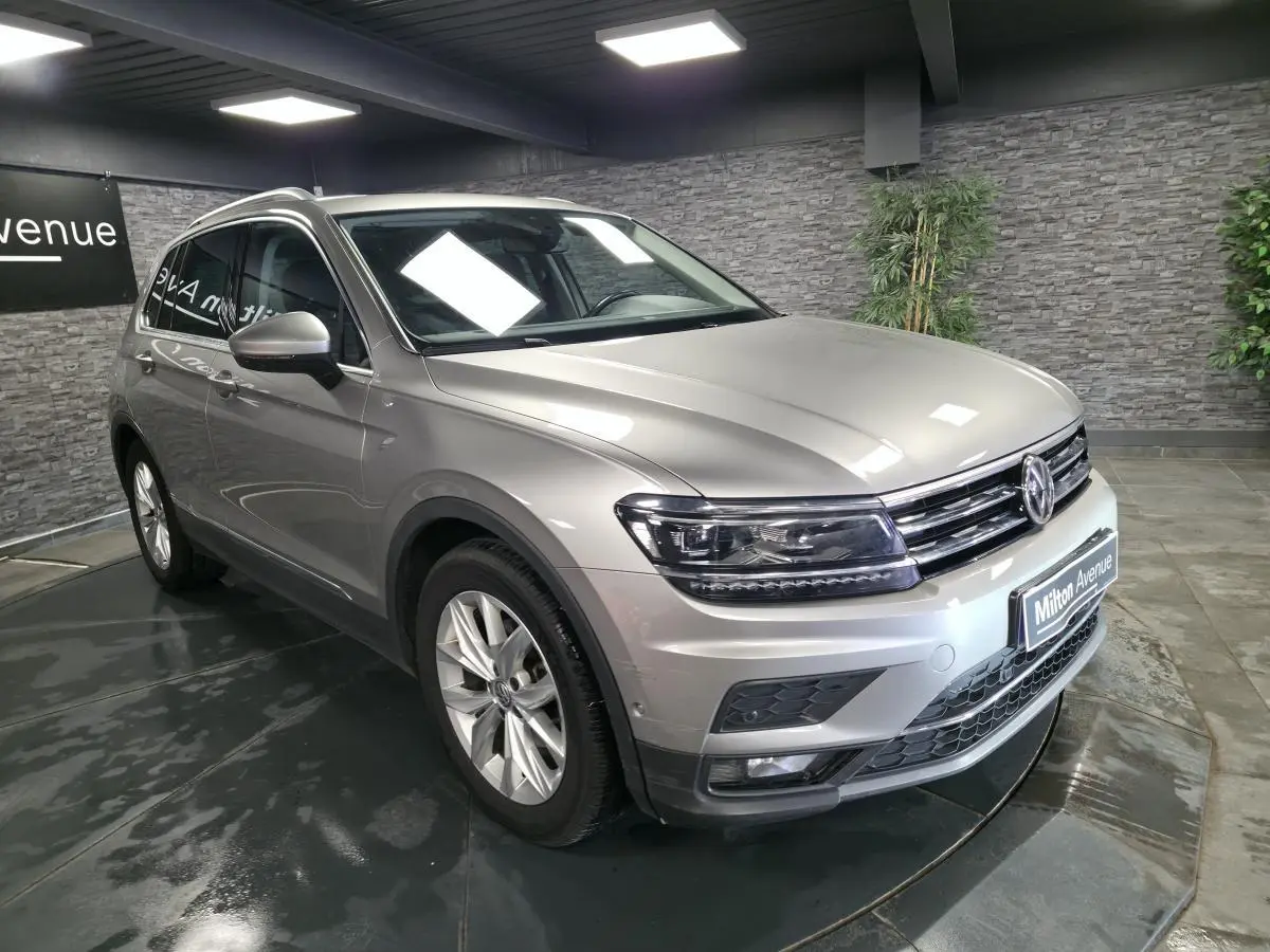 Volkswagen Tiguan gris métallisé vu en 3/4 avant droit dans un showroom avec jantes alliage 18 pouces.