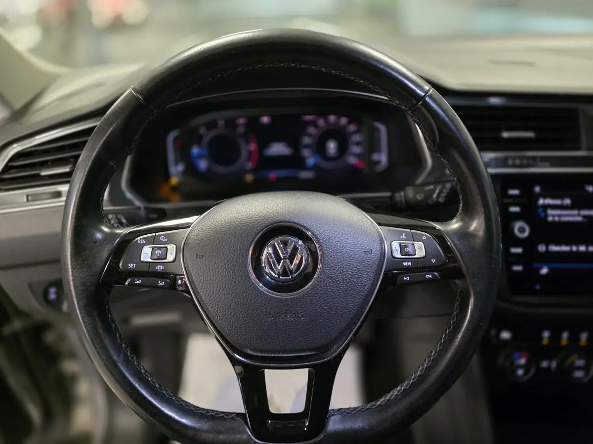 Volant cuir noir Volkswagen Tiguan 2020 vu de face avec commandes multifonctions et tableau de bord digital flou.