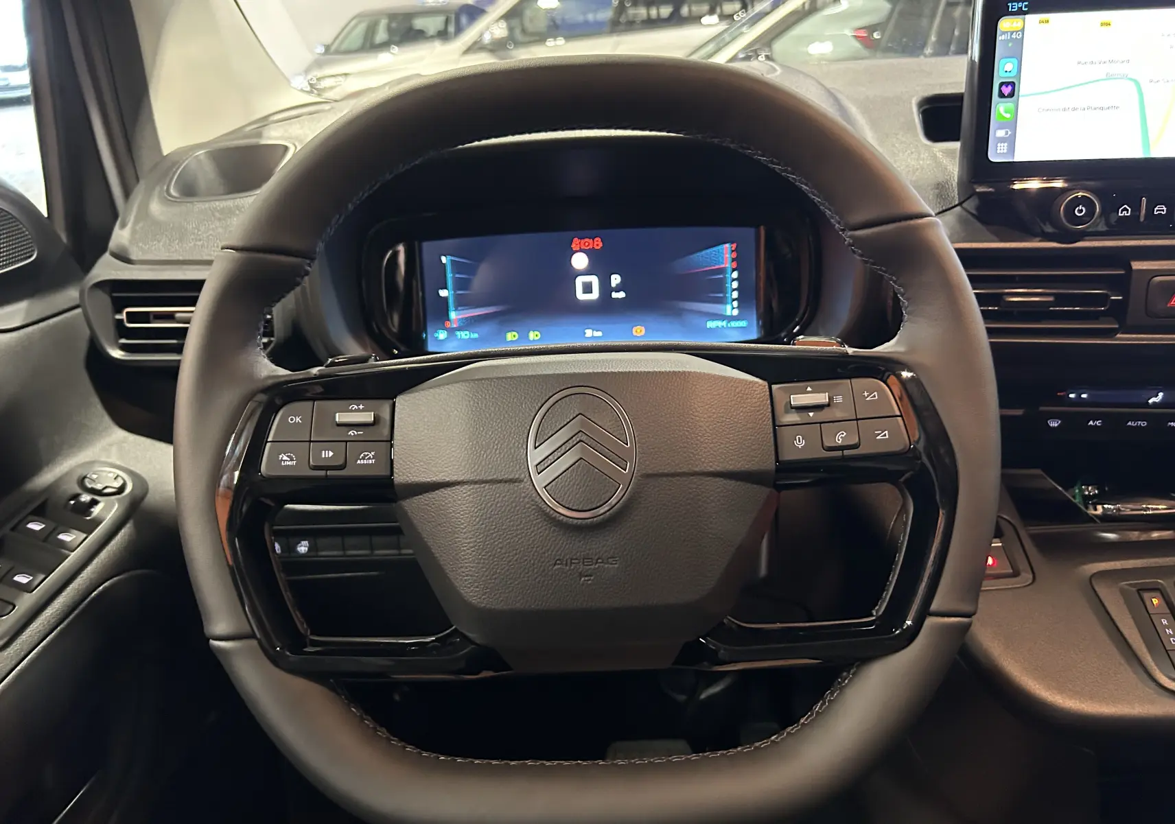 Vue rapprochée du volant noir de la Citroën Berlingo Multispace 2025 avec tableau de bord numérique et écran tactile latéral.