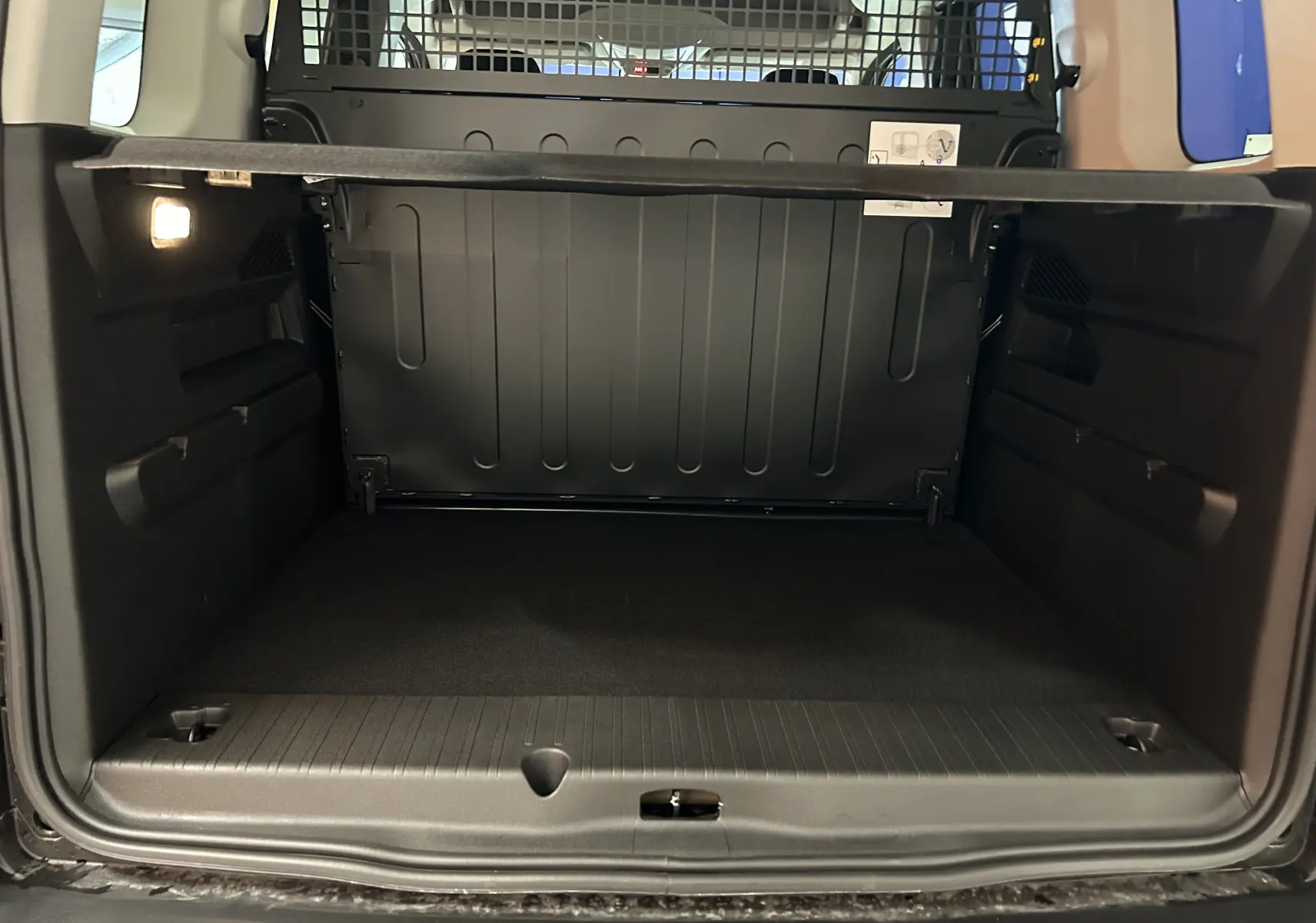 Vue intérieure du coffre spacieux du Citroën Berlingo Multispace 2025, avec séparation métallique et éclairage latéral.