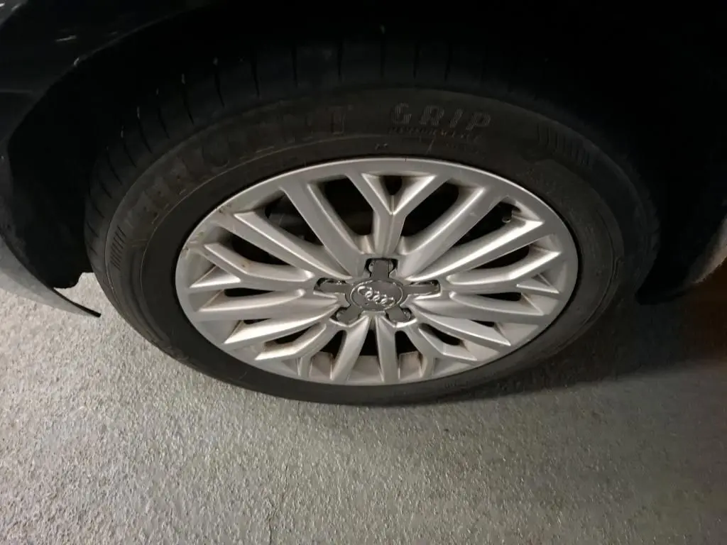 Gros plan sur la jante en aluminium 10 branches argentée de l'Audi A3 Sportback noire, vue côté roue avant.