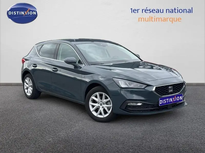 Vue 3/4 avant droite d'une SEAT LEON 2025 gris graphène métallisé avec jantes alliage et calandre noire distinctive.