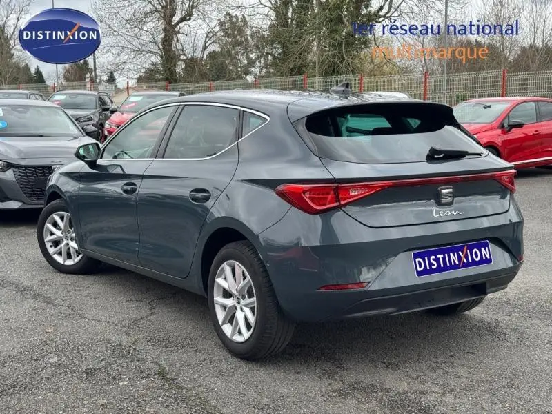 Vue 3/4 arrière droite d'une SEAT Leon 2025 gris graphène métallisé avec feux arrière étirés et jantes argentées.