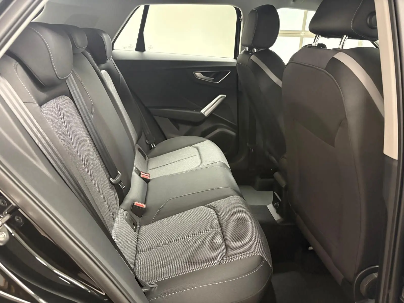 Vue intérieure côté droit des sièges arrière en tissu gris et noir de l’Audi Q2 35 TFSI S Line 2026 Noir Mythic.