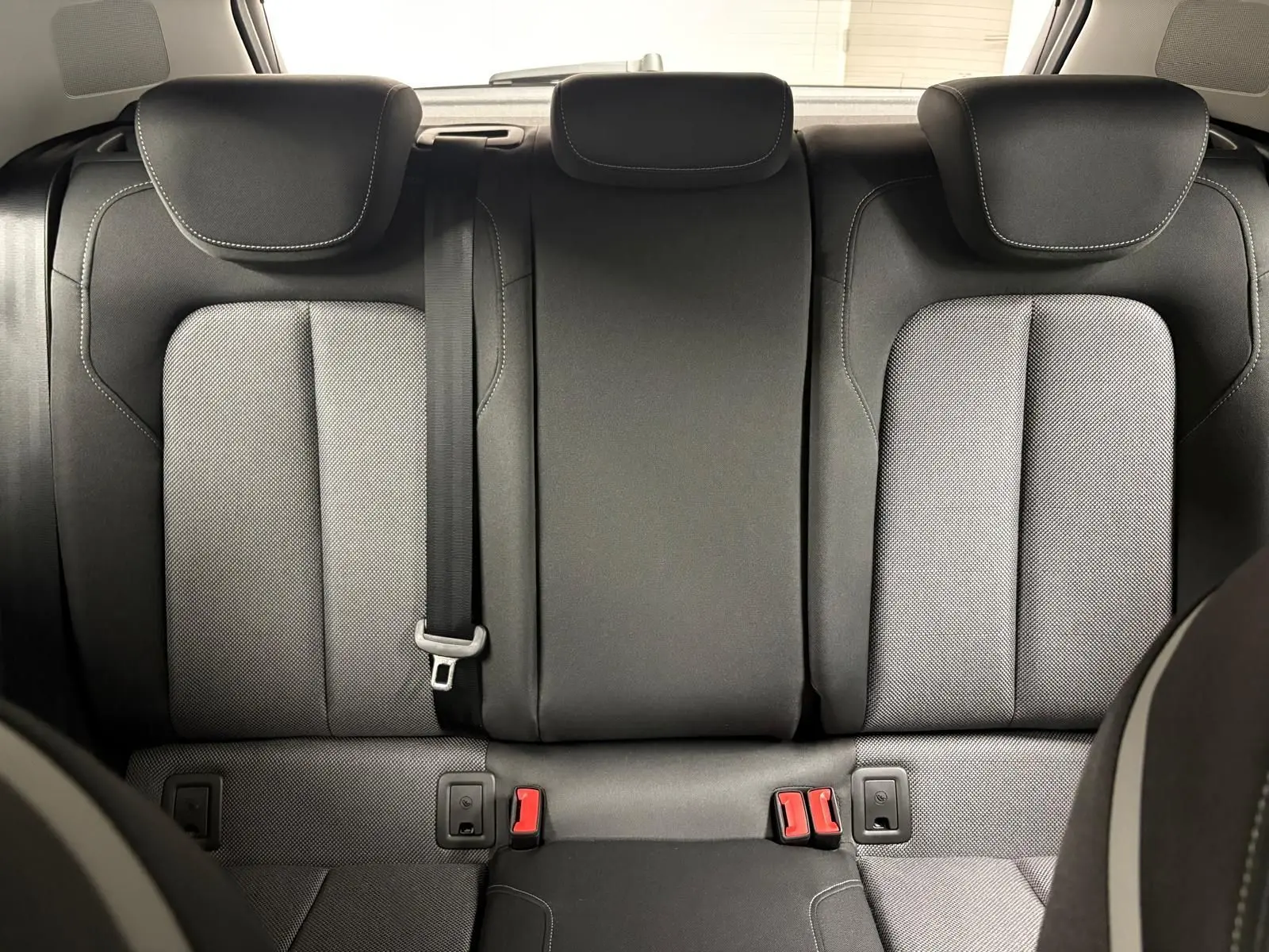 Vue arrière des sièges arrière en tissu noir et gris de l'Audi Q2 35 TFSI S Line 2026, avec ceinture de sécurité centrale visible.