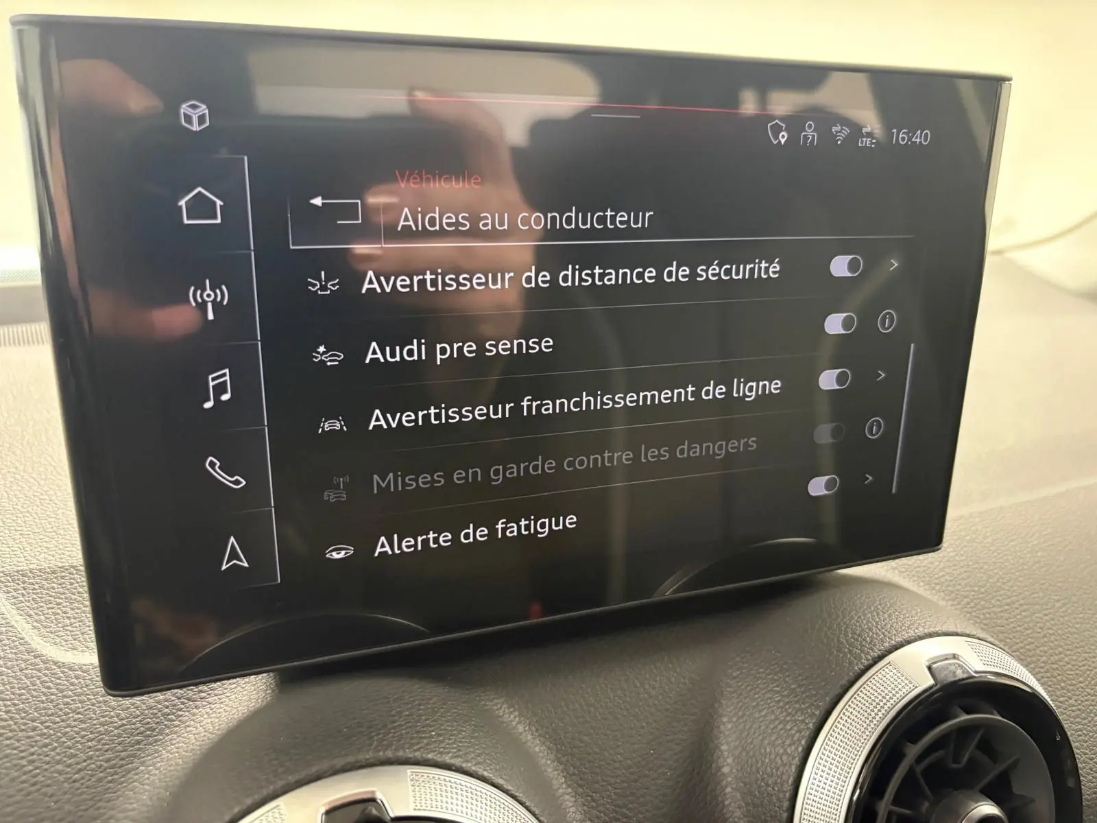 Écran central tactile affichant les aides au conducteur dans l’habitacle d’un Audi Q2 Noir Mythic, vue de face.