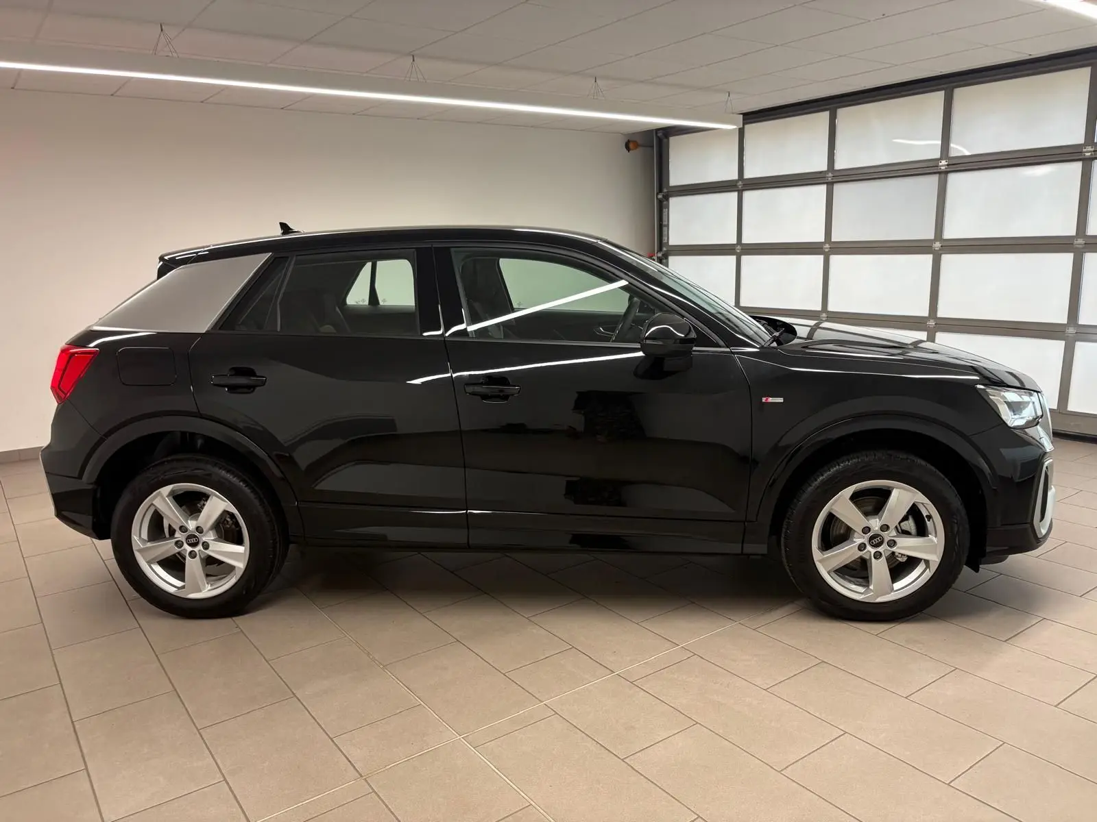 Audi Q2 35 TFSI S Line noir mythic vue de profil côté gauche dans un garage lumineux.