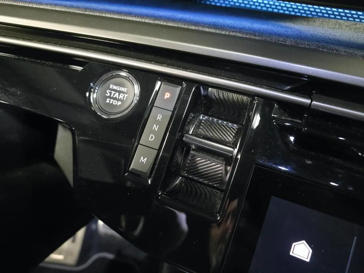 Détail de la console centrale noire brillante du Peugeot 3008 2025 avec bouton start/stop et commandes de boîte automatique.