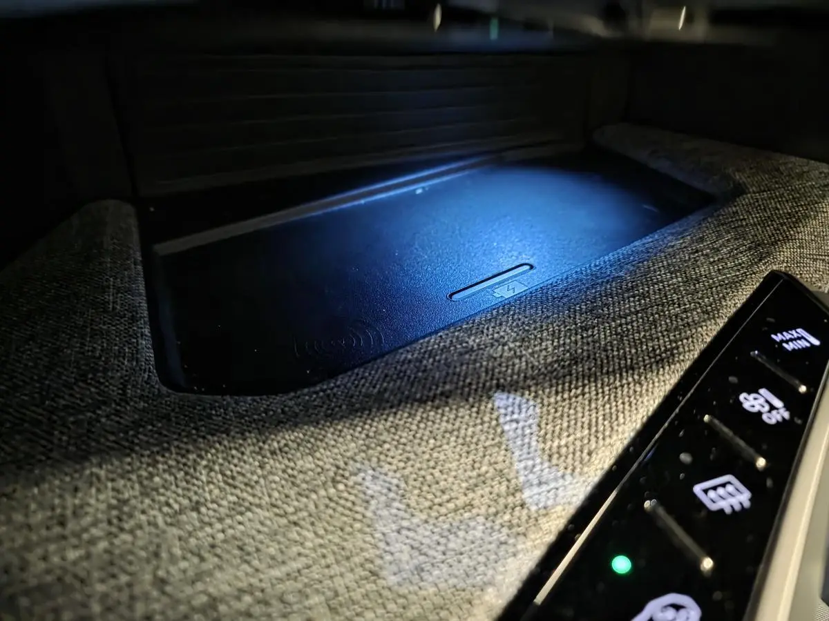 Gros plan sur la console centrale tissu Rimini avec chargeur smartphone sans fil éclairé du Peugeot 3008 noir 2025.