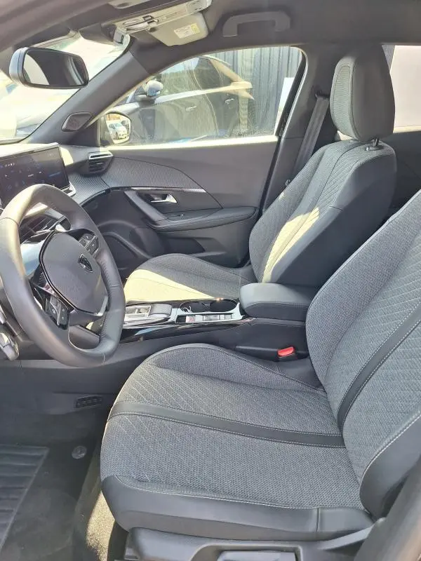 Vue intérieure côté conducteur du Peugeot 2008 Hybrid 136 Allure 2025, sièges gris et cockpit numérique visible.