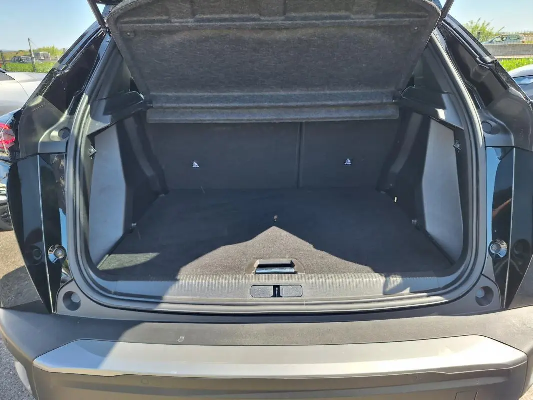 Coffre ouvert vu de l'arrière d'un Peugeot 2008 noir, montrant l'espace de chargement vide et la garniture intérieure.
