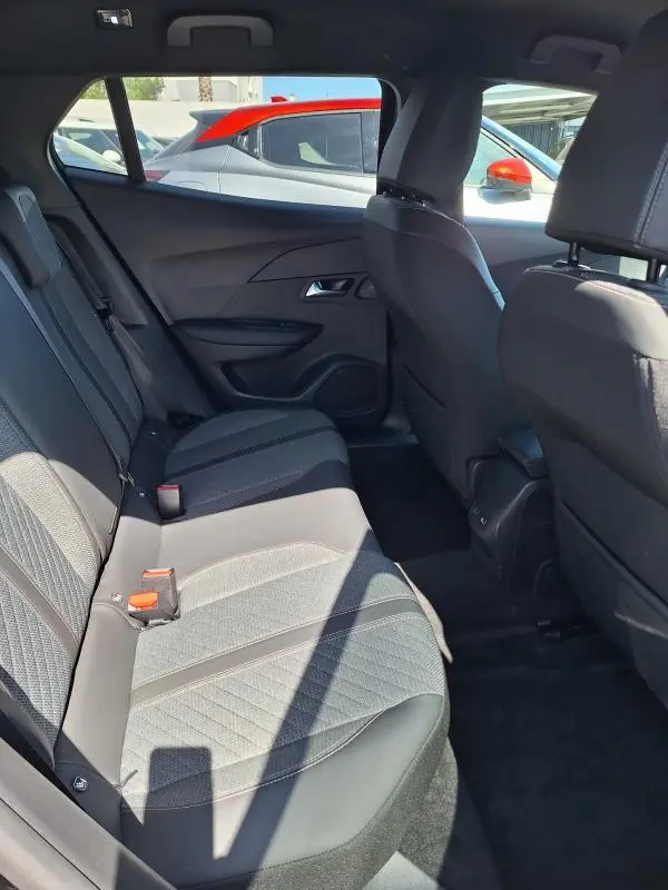 Vue intérieure côté droit des sièges arrière du Peugeot 2008 Hybrid 136 Allure noir, avec sellerie tissu et détails contrastés.