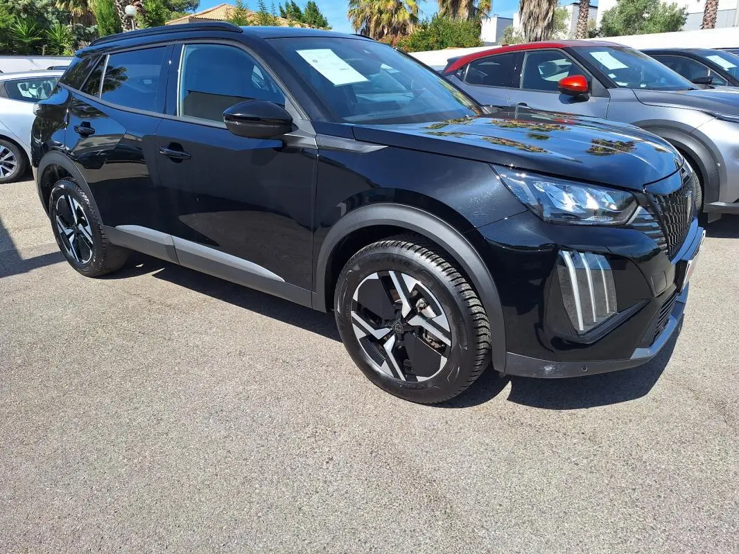 Peugeot 2008 Hybrid noir en 3/4 avant droit, avec barres de toit et jantes alliage 17 pouces visibles.