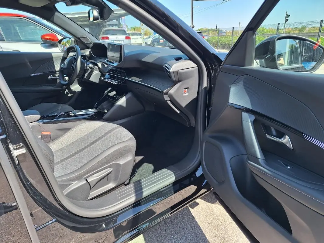 Vue intérieure côté conducteur d’un Peugeot 2008 Hybrid noir, montrant le tableau de bord moderne et l’écran tactile.
