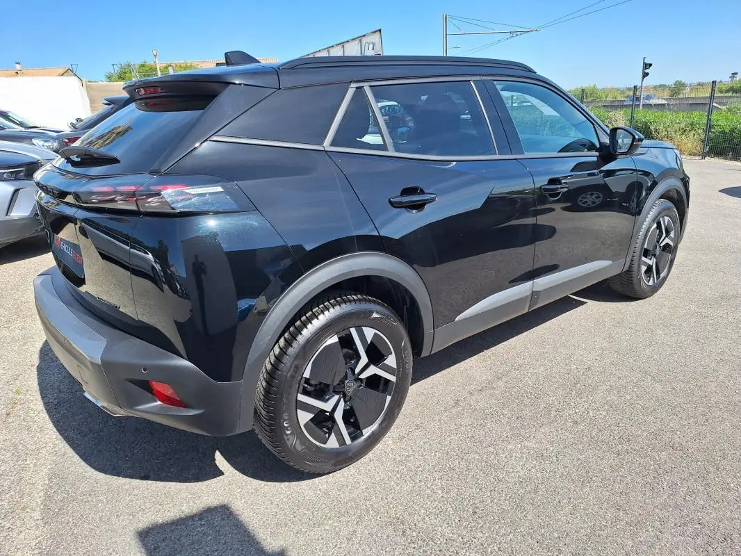 Vue 3/4 arrière droite d’un Peugeot 2008 Hybrid noir avec barres de toit et jantes alliage 17 pouces.