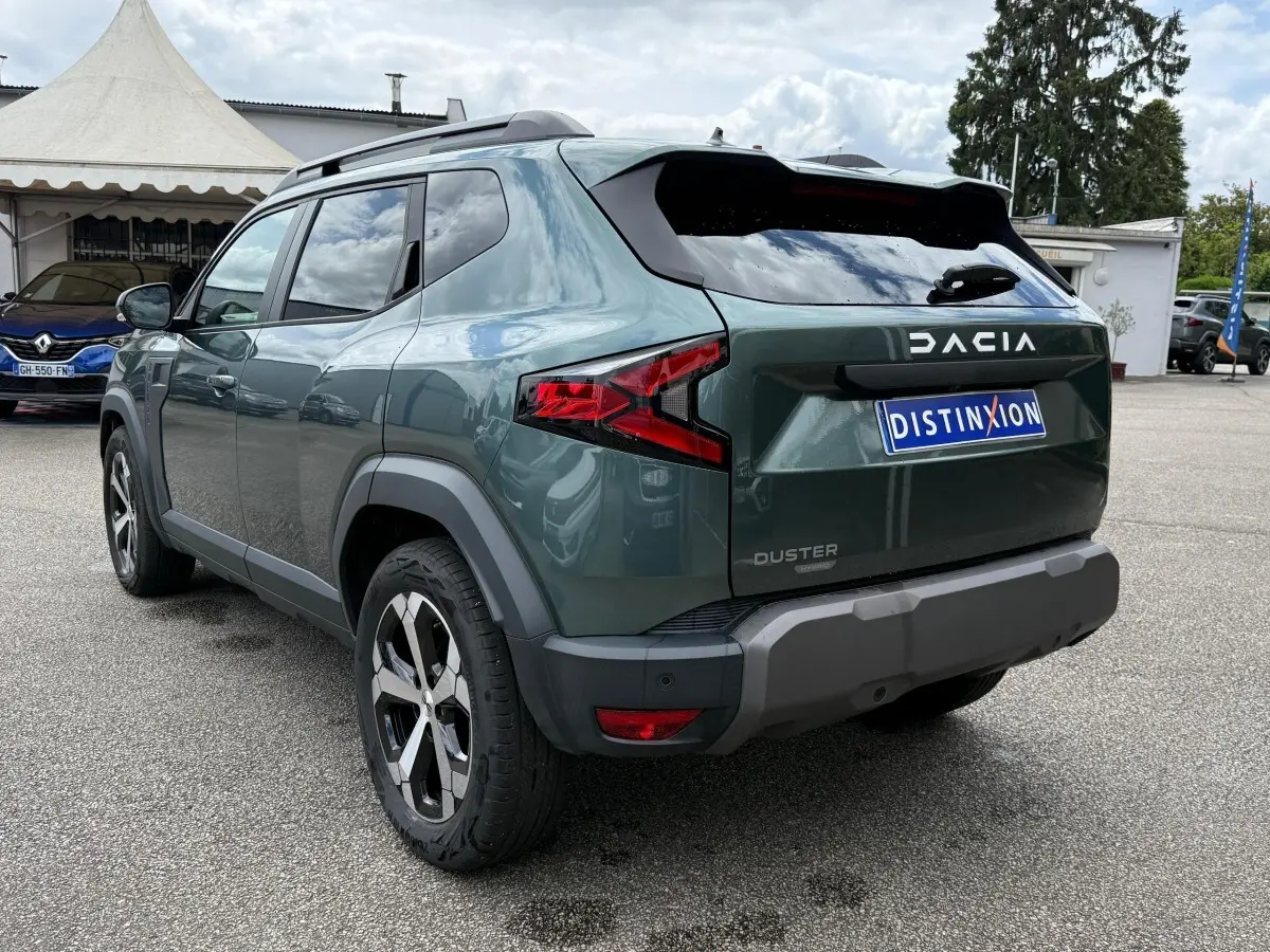 Vue 3/4 arrière droite du Dacia Duster Hybrid 140 vert cèdre avec feux arrière LED et jantes alliage bicolores.