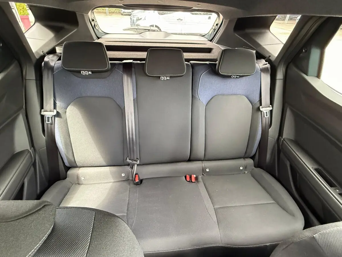 Vue arrière intérieure sur la banquette arrière noire et grise du Dacia Duster Hybrid 140 Journey 2025.