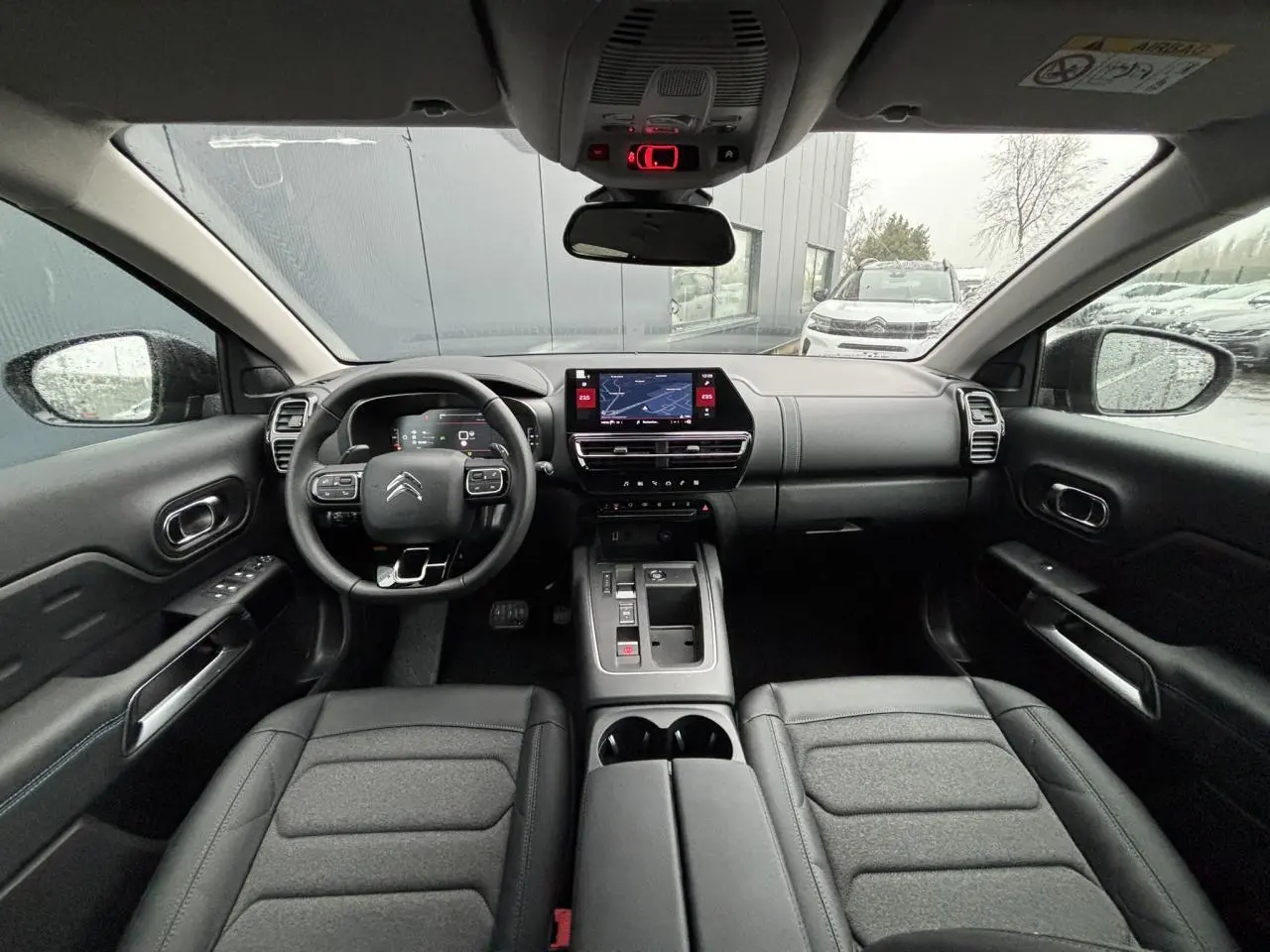 Vue intérieure frontale du Citroën C5 Aircross 2025, tableau de bord noir avec écran tactile et volant multifonction.