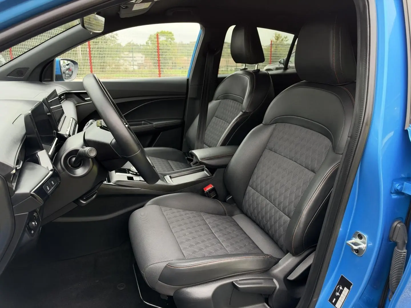 Vue intérieure côté conducteur du MG3 1.5 Hybrid+ 195ch Luxury 2025, sièges noir simili-cuir/tissu, portière Como Blue métallisé ouverte.