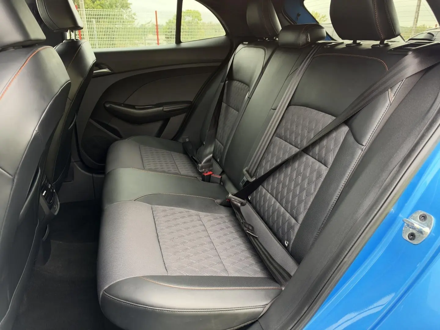 Vue intérieure côté droit des sièges arrière en similicuir noir avec surpiqûres orange du MG3 1.5 Hybrid+ 195ch Luxury Como Blue métallisé 2025.