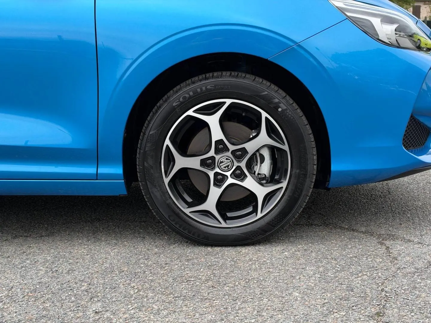 Gros plan sur la roue avant gauche et la jante alu au design sportif du MG3 1.5 Hybrid+ 195ch Luxury en Como Blue métallisé.
