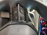 Gros plan sur les commandes au volant cuir du Peugeot 5008 bleu célèbes, mettant en valeur les touches multimédia et vocales.