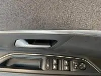 Gros plan sur la commande des vitres et le bouton de réglage des rétroviseurs côté conducteur d'une Peugeot 5008.