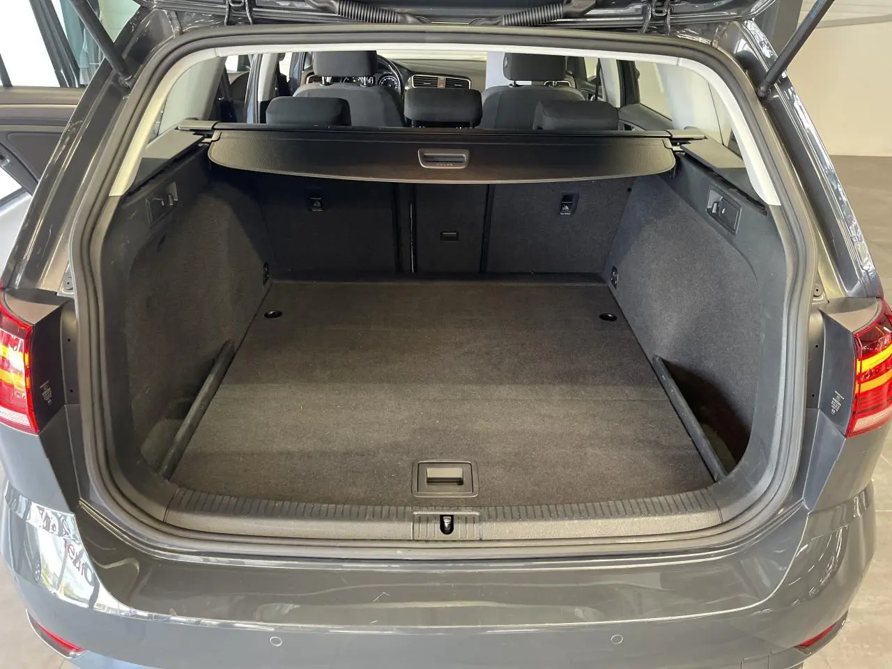 Coffre ouvert d'une Volkswagen Golf SW 1.6 TDI gris foncé, vue arrière montrant l'espace de chargement vide.