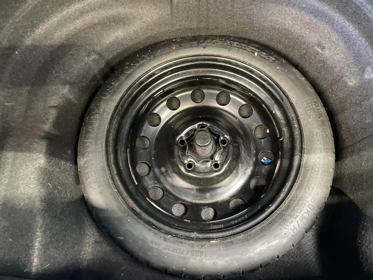 Gros plan sur la roue de secours noire en acier dans le coffre d'une Volkswagen Golf SW gris foncé 2017