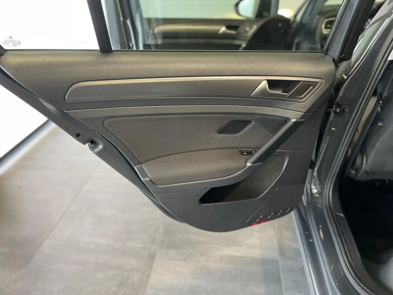 Porte arrière droite ouverte d'une Volkswagen Golf SW gris foncé, montrant le revêtement intérieur noir avec insert décoratif chromé.