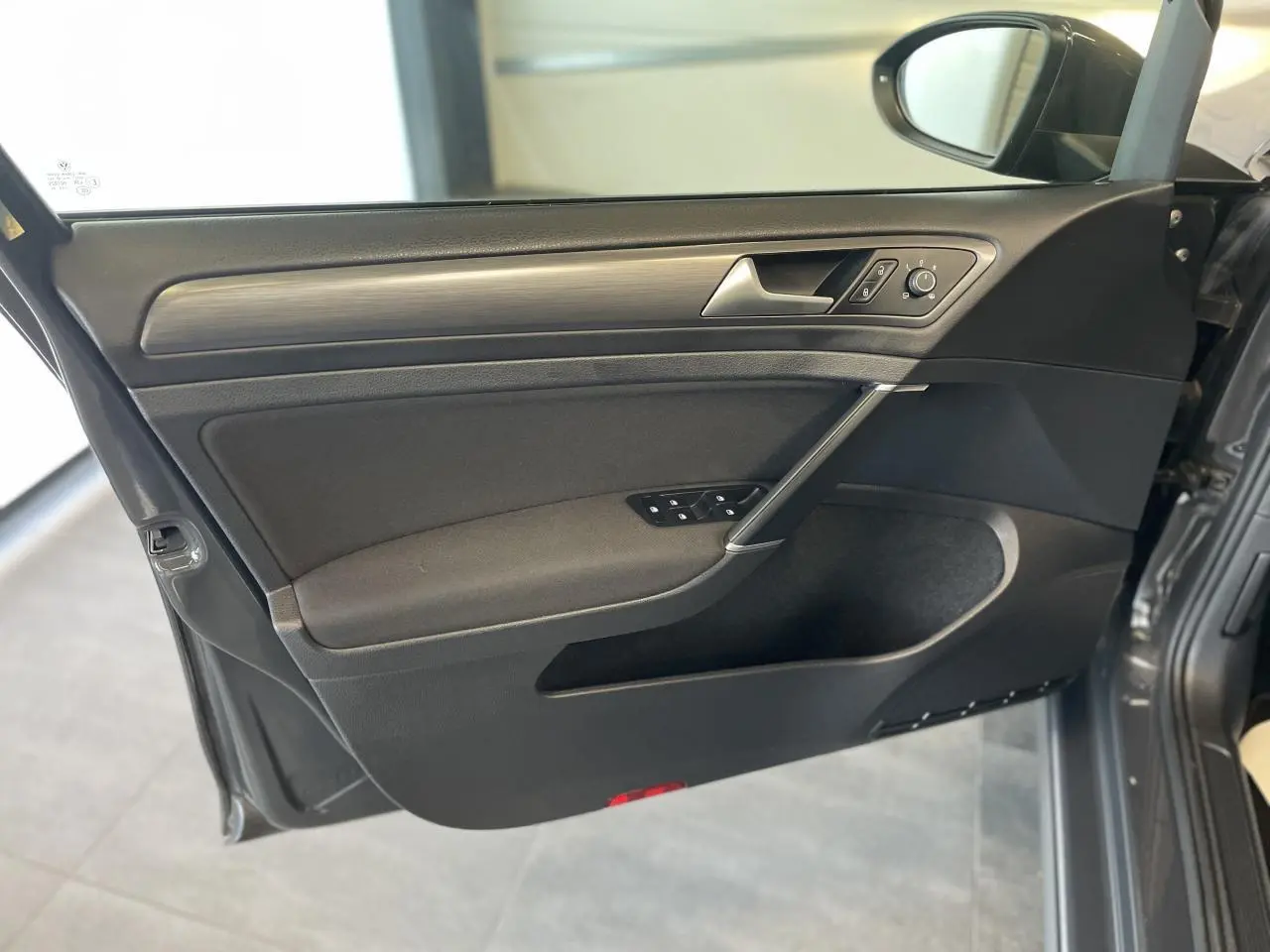 Intérieur côté gauche de la porte avant d'une Volkswagen Golf SW gris foncé, avec commandes électriques et insert décoratif.