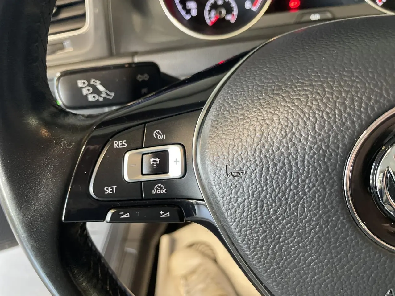 Gros plan sur le volant cuir noir de la Volkswagen Golf SW 2017, avec commandes de régulateur de vitesse visibles.