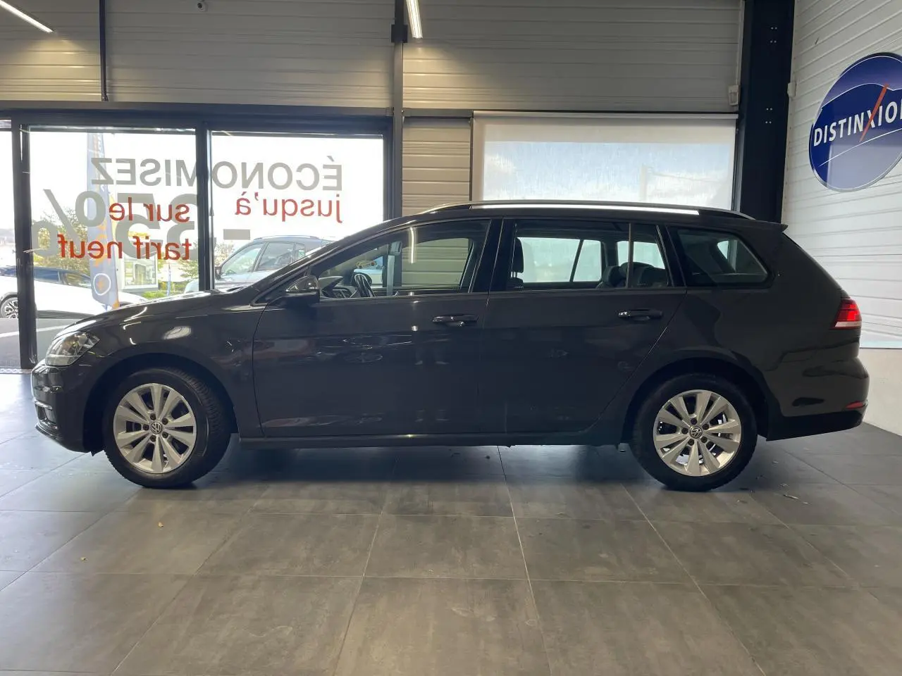 Profil côté gauche d'une Volkswagen Golf SW gris foncé 2017 en intérieur, avec jantes alliage 16 pouces visibles.