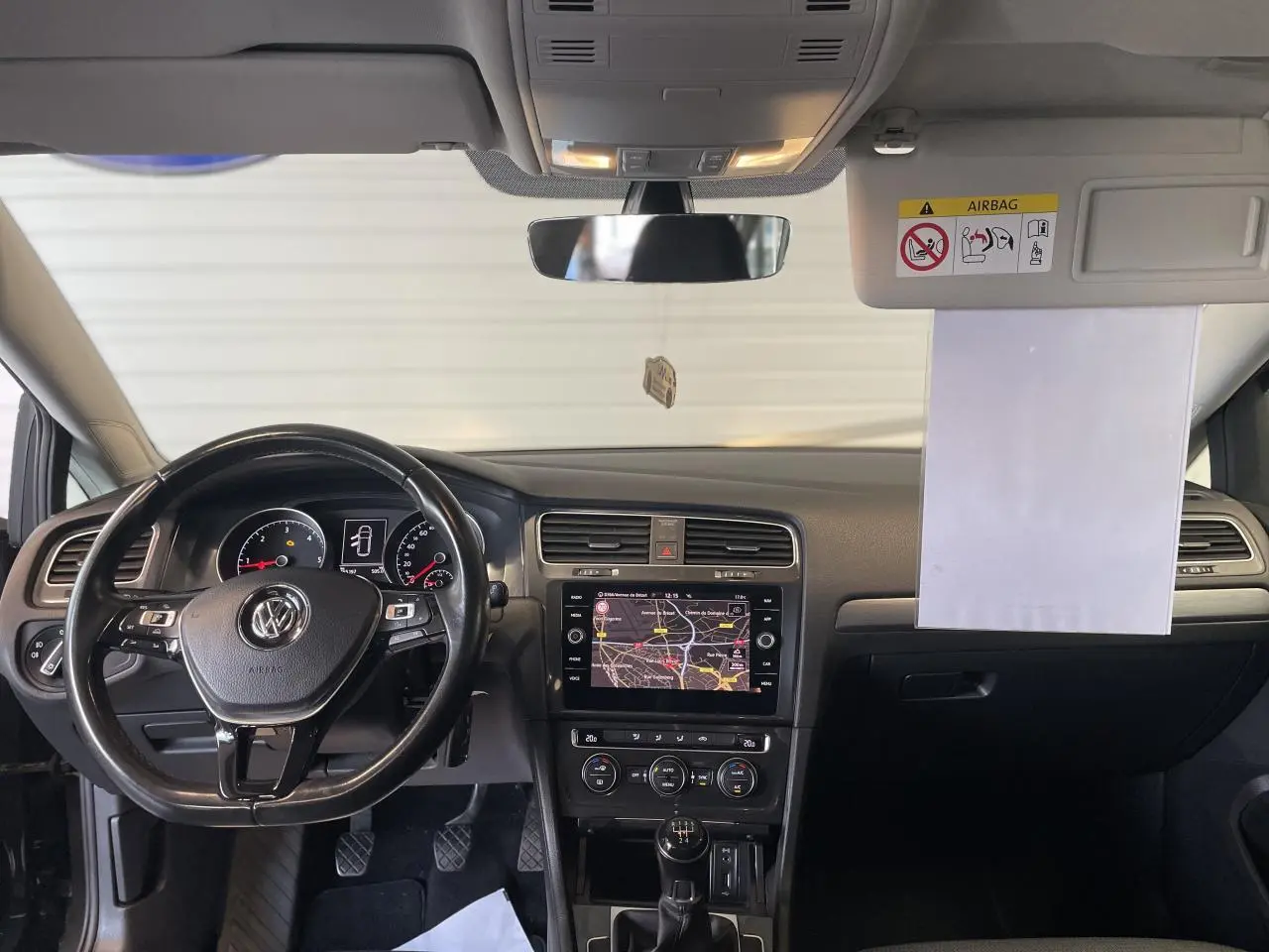 Vue frontale de l'intérieur noir de la Volkswagen Golf SW 2017, montrant le volant cuir et l'écran tactile central avec navigation.