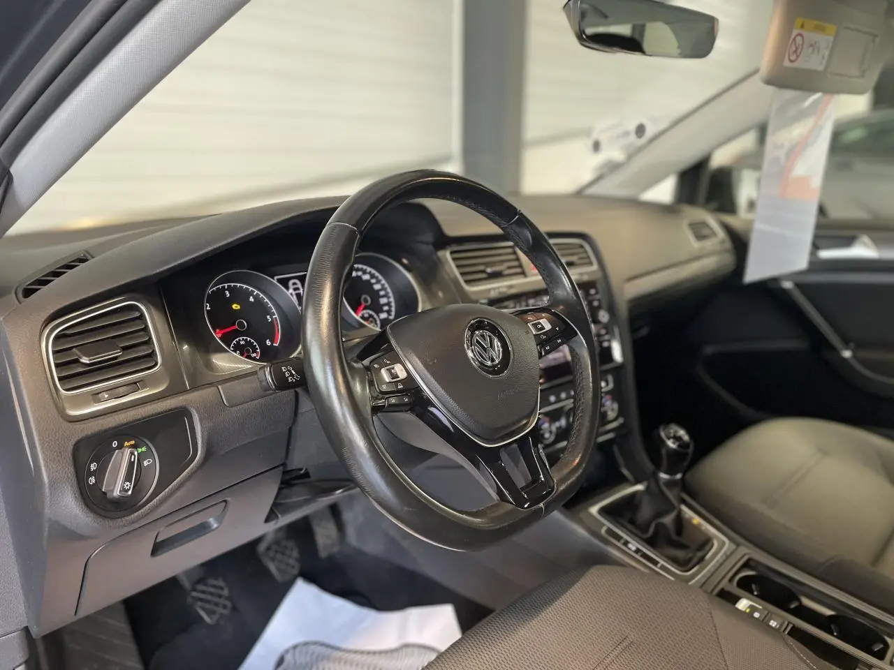 Intérieur de Volkswagen Golf SW 2017, vue côté conducteur sur volant cuir multifonction et levier de vitesses manuel.