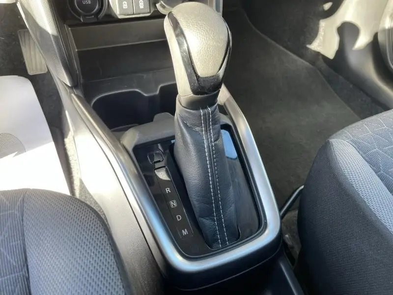 Gros plan sur la commande de la boîte automatique noire avec surpiqûres blanches dans une Suzuki Swift blanche 2025.