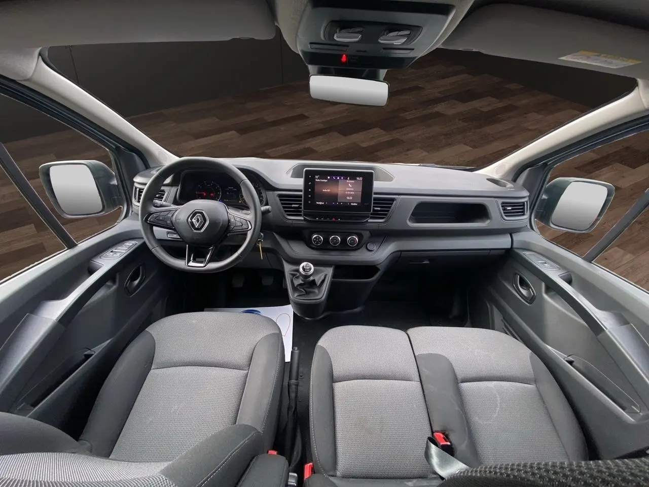 Vue intérieure avant du Renault Trafic Combi 2023 gris platine, montrant le tableau de bord avec écran tactile et volant multifonction.