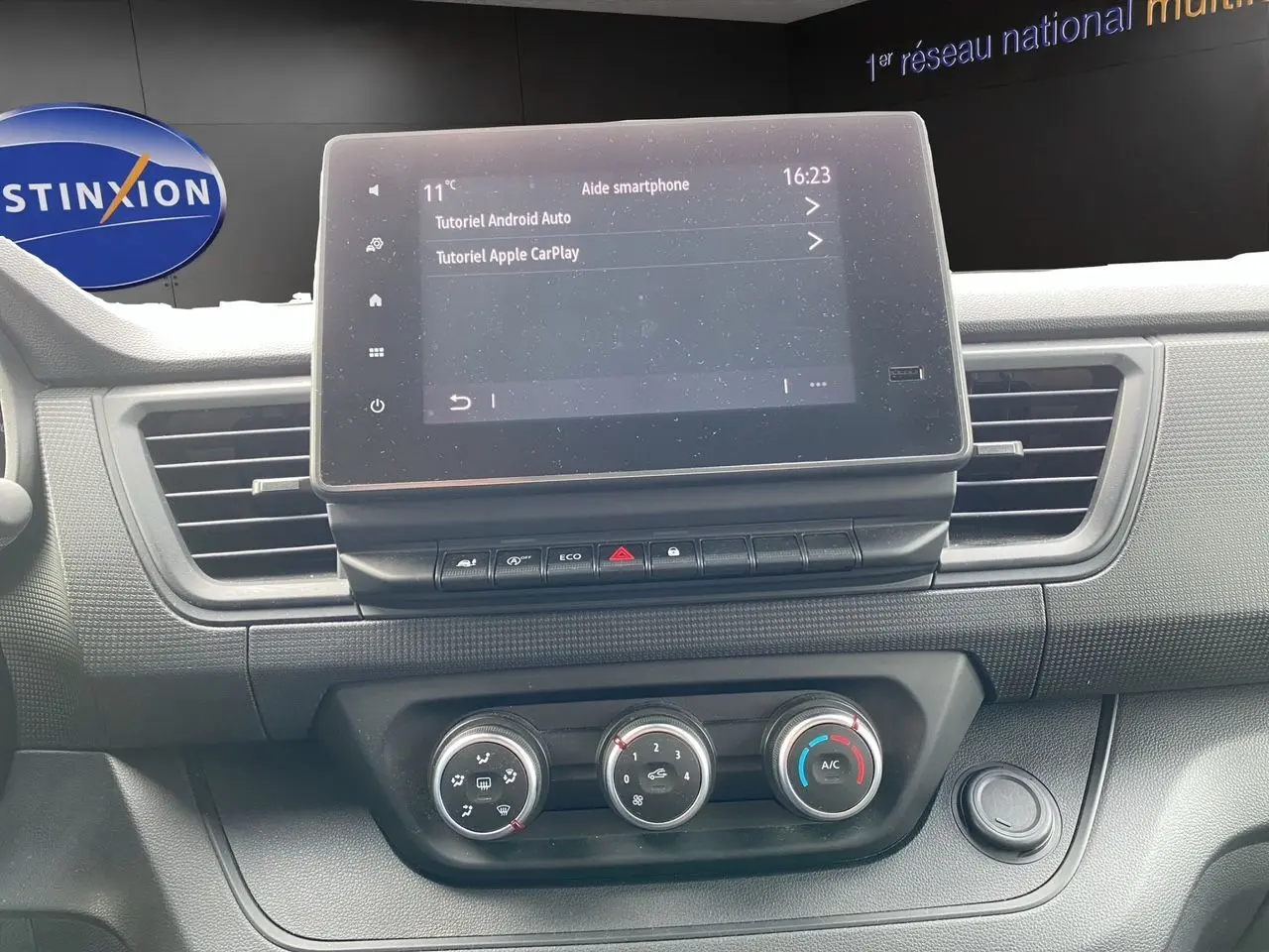 Vue rapprochée du tableau de bord du Renault Trafic Combi gris platine 2023, avec écran tactile et commandes de climatisation.