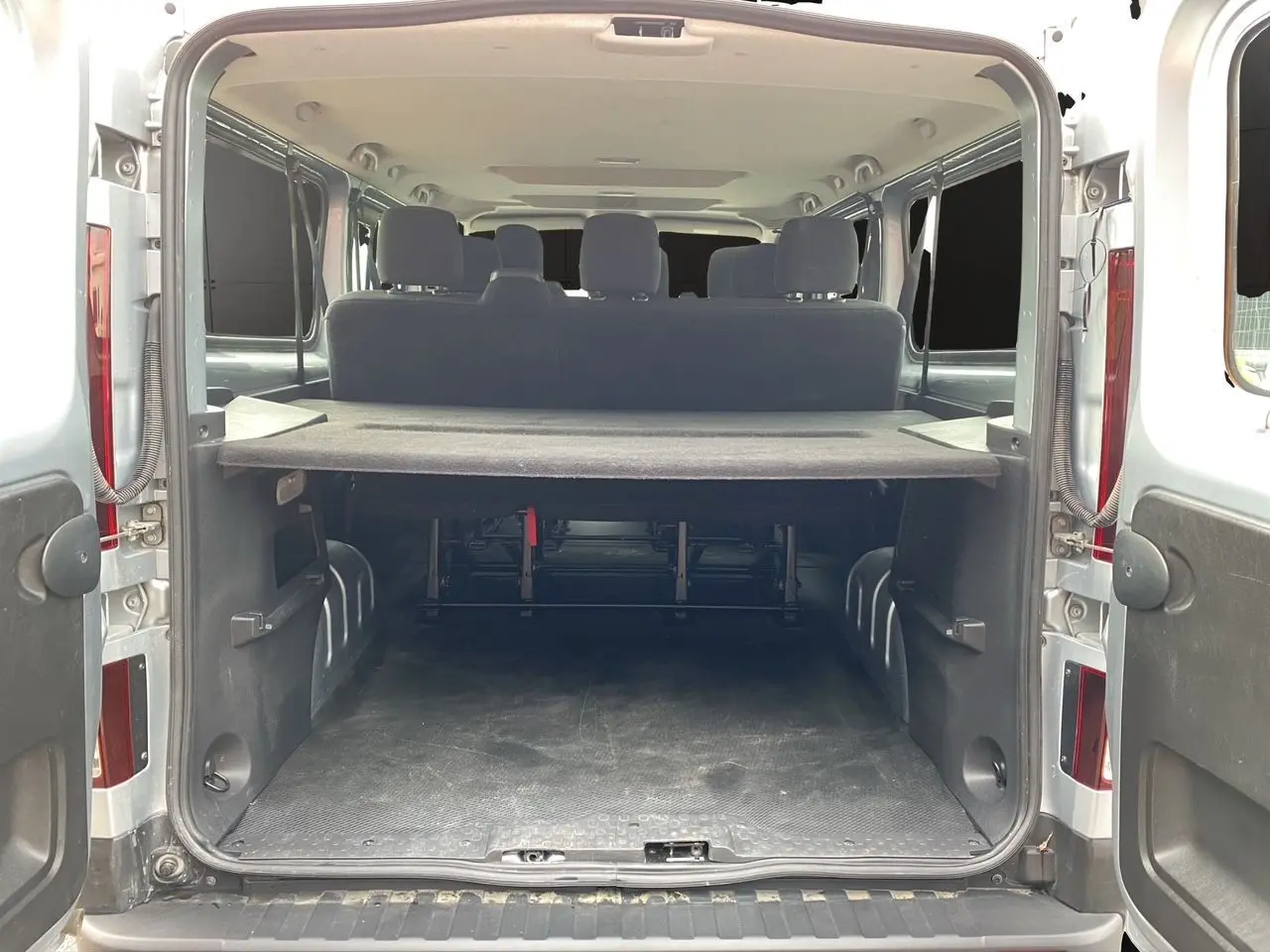 Vue arrière ouverte du Renault Trafic Combi gris platine 2023, montrant l'espace de chargement et les sièges arrière.