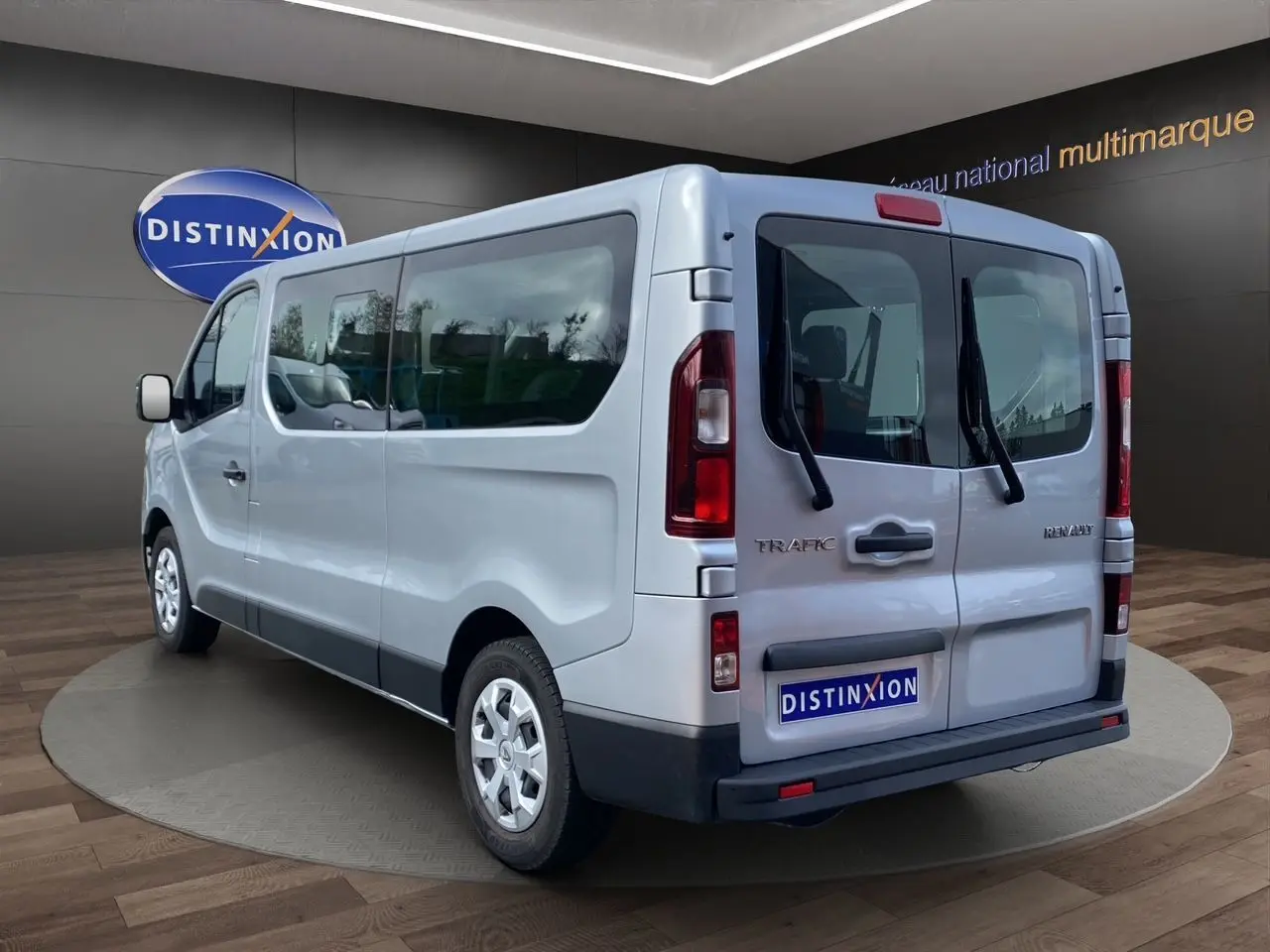 Vue 3/4 arrière droite d’un Renault Trafic Combi gris platine 2023 avec portes arrière vitrées et jantes acier.