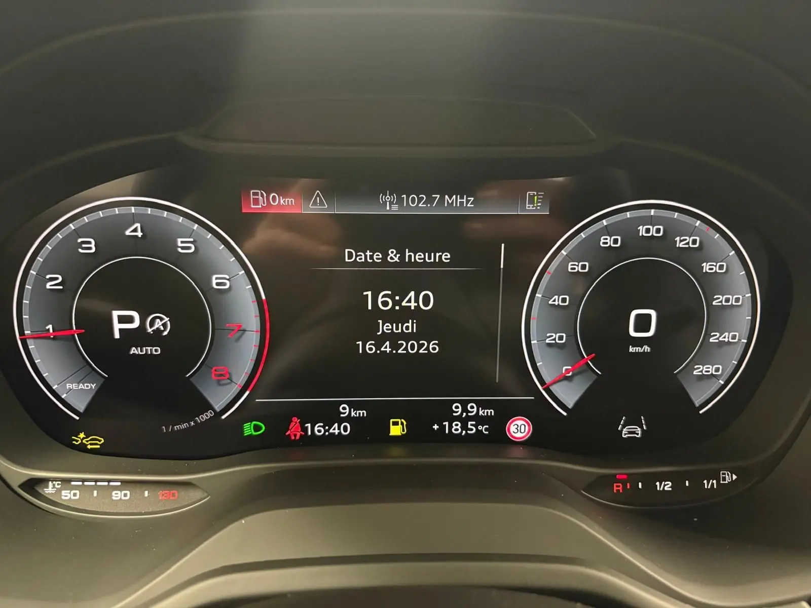 Vue rapprochée du tableau de bord numérique de l'Audi Q2 35 TFSI 150 S Line affichant la date, l'heure et les compteurs.