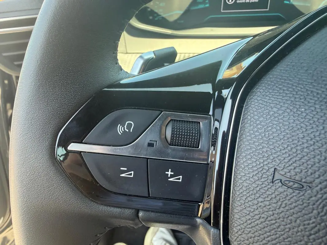 Gros plan sur les commandes vocales et volume au volant du Peugeot 2008 Hybrid 136 e-DCS6 Style noir, intérieur moderne.
