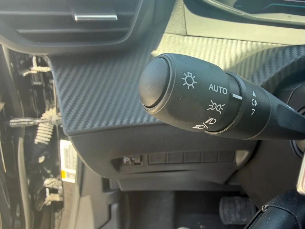 Gros plan sur la commande d’éclairage du tableau de bord du Peugeot 2008 Hybrid 136 e-DCS6 Style noir, intérieur carbone.