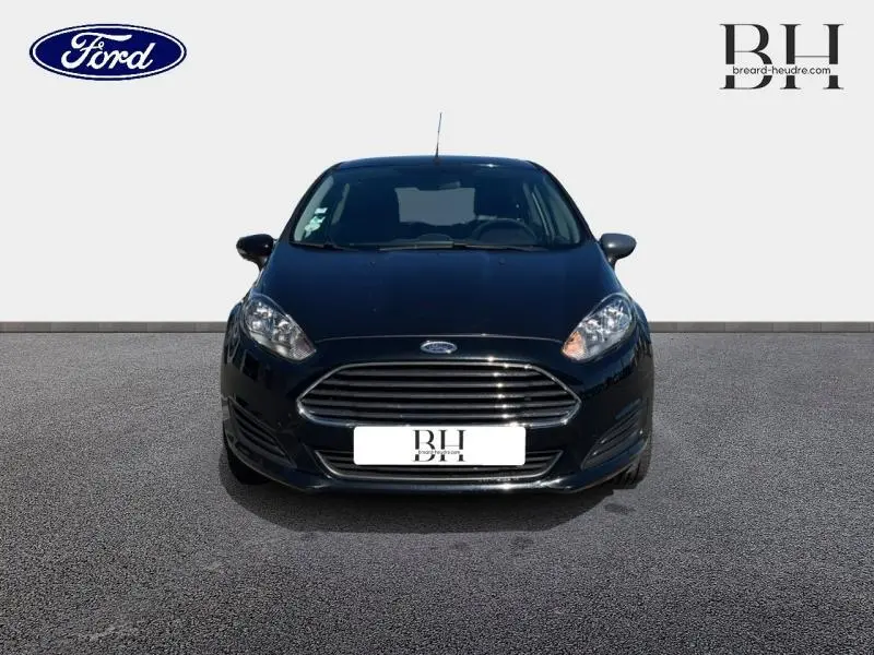 Vue de face d'une Ford Fiesta noire 2015 avec calandre chromée et phares allongés, sur fond neutre.