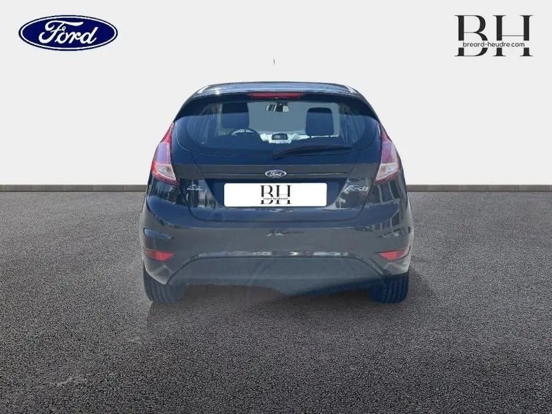 Vue arrière d'une Ford Fiesta noire 2015, version 1.5 TDCi Edition 5 portes, sur sol gris uniforme.