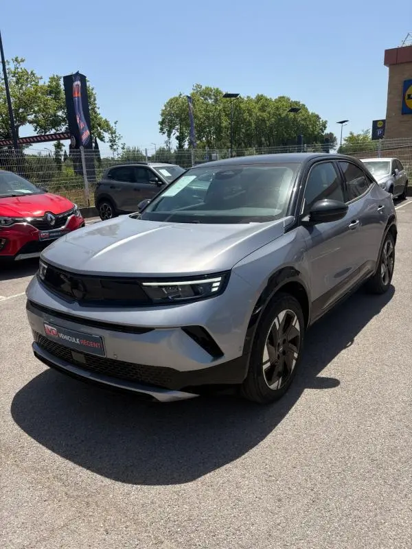 Opel Mokka électrique gris en 3/4 avant droit, avec jantes alliage 17 pouces et vitres surteintées.