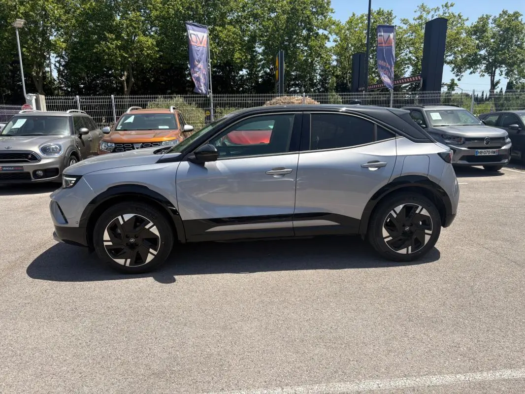Opel Mokka électrique gris vue de profil côté gauche, avec toit noir et jantes alliage 17 pouces, vitres surteintées.