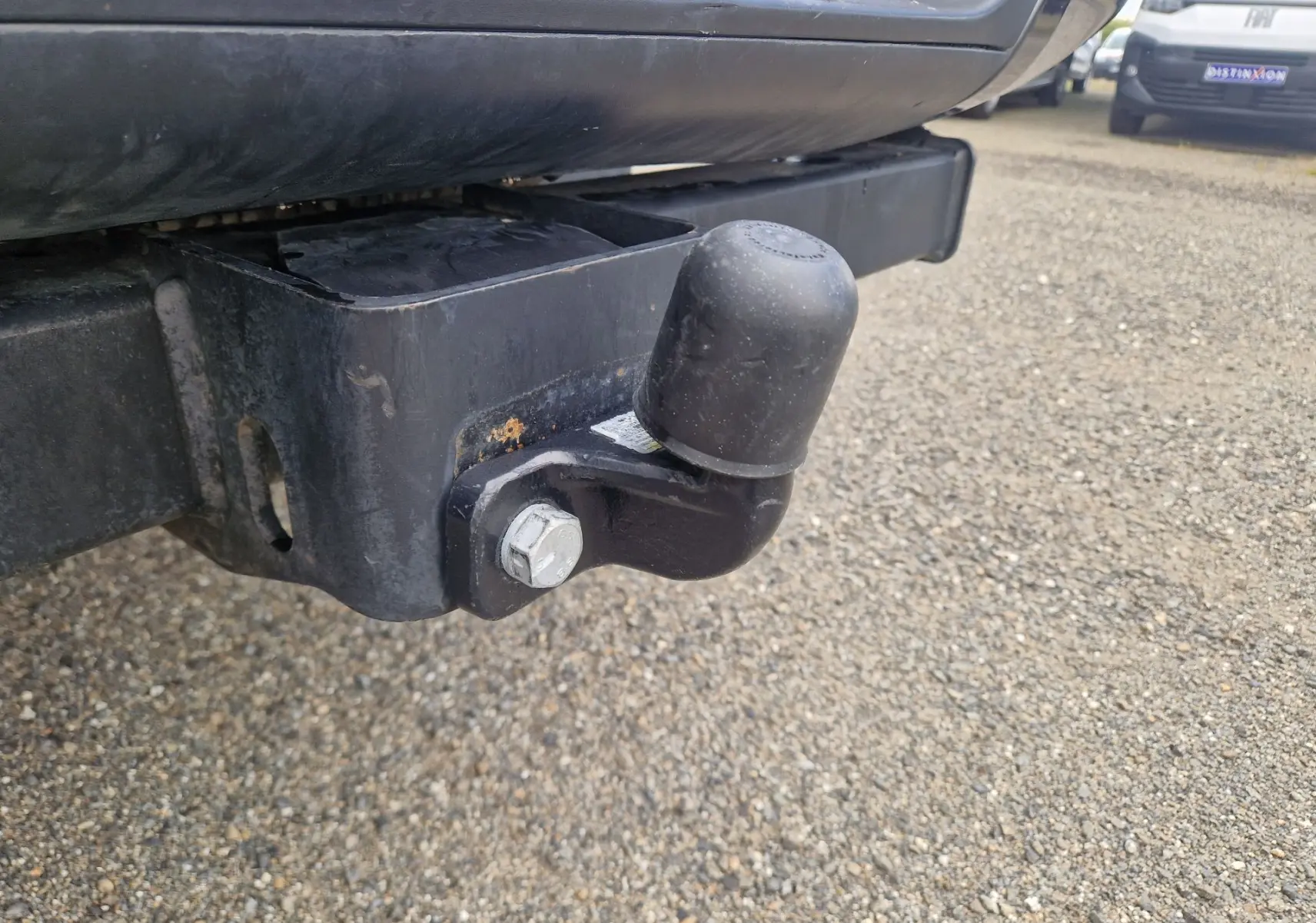 Gros plan sur l'attelage arrière noir du Ford Ranger Super Cabine blanc, avec protection en caoutchouc sur la boule.