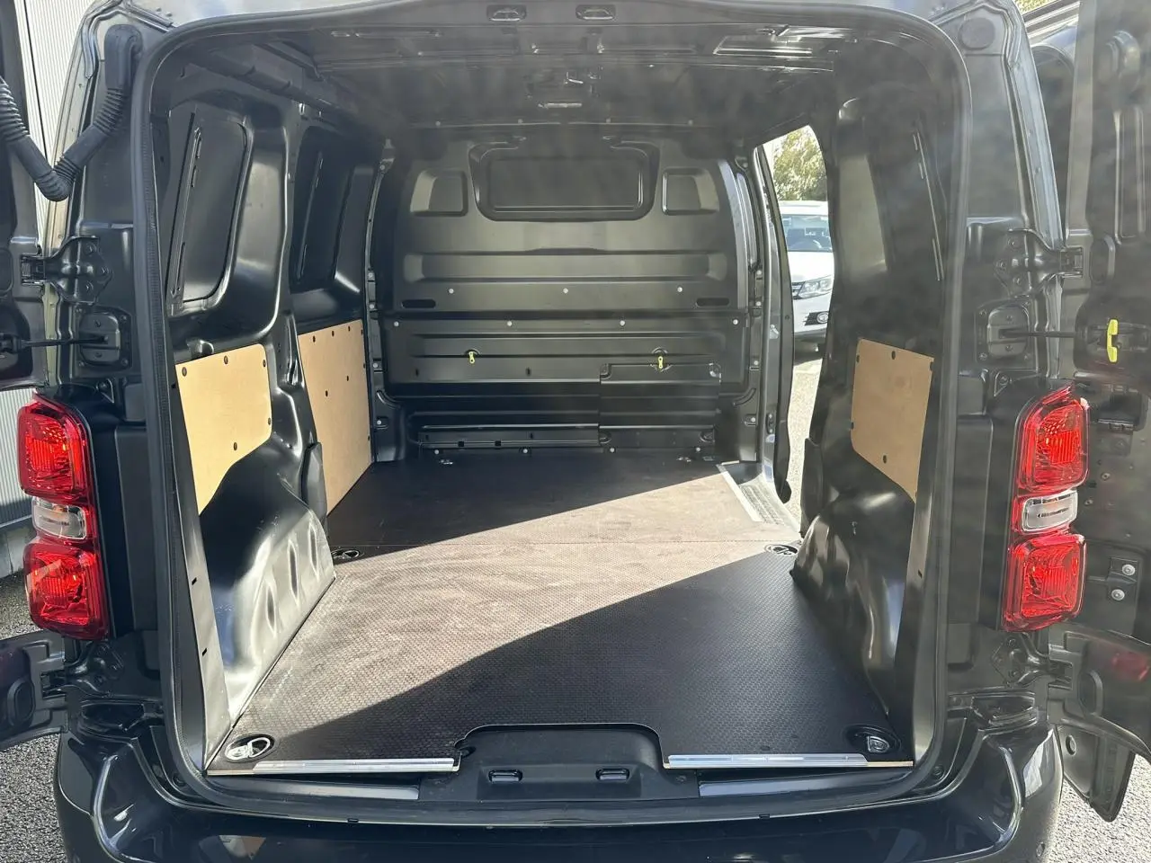 Vue arrière ouverte du FIAT Scudo Fourgon gris Platinium montrant l'espace de chargement avec plancher bois antidérapant.