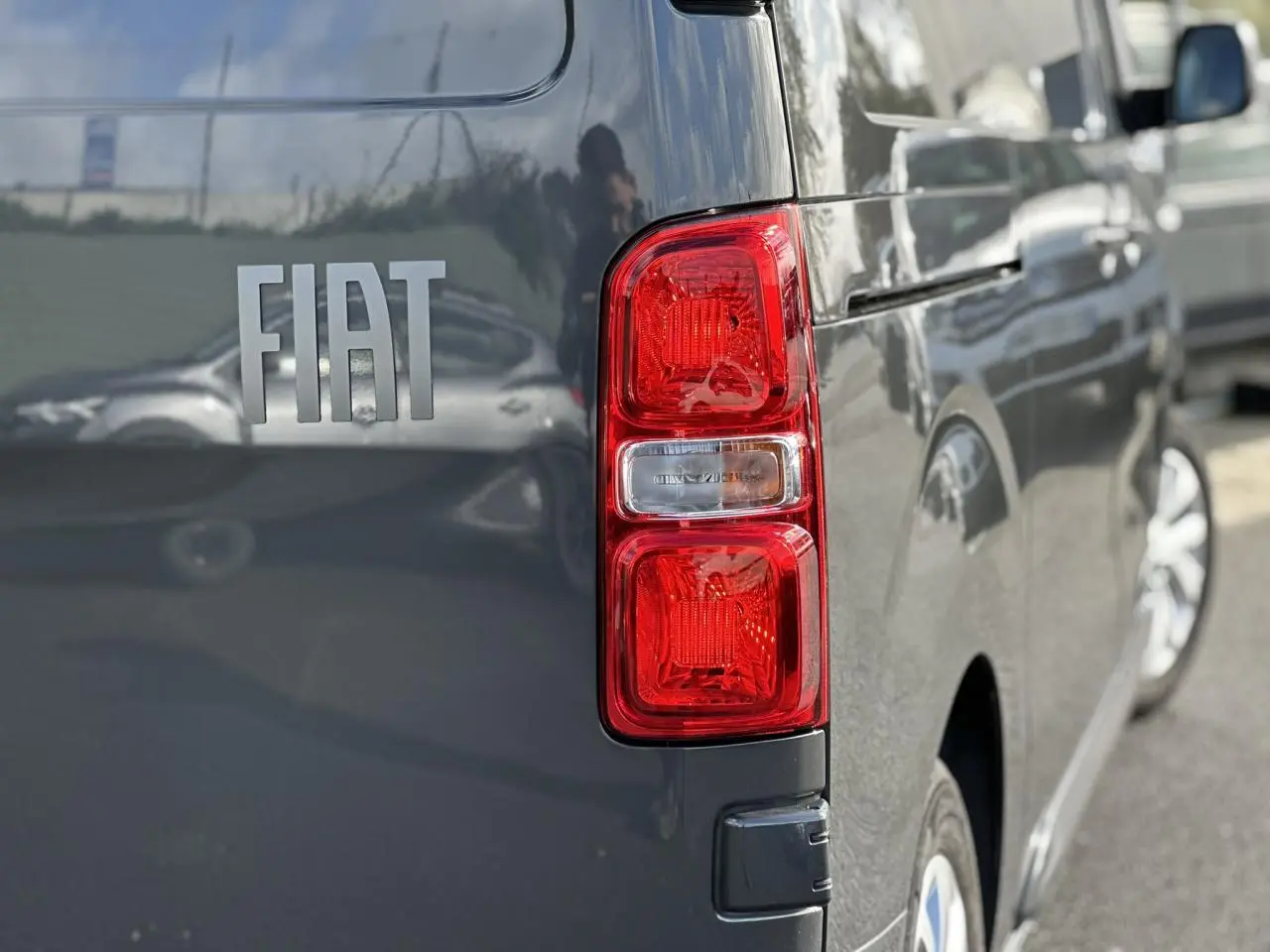 Gros plan sur le feu arrière droit d’un FIAT Scudo Fourgon gris Platinium avec reflet de la carrosserie.